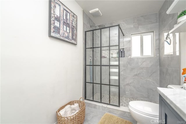 bathroom featuring toilet, vanity, tile patterned flooring, and a tile shower