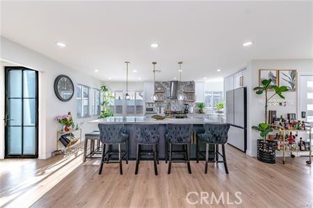 kitchen featuring light hardwood / wood-style floors, a center island, hanging light fixtures, white cabinets, and white refrigerator