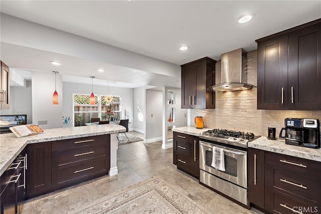 kitchen with gas range, hanging light fixtures, wall chimney exhaust hood, light stone counters, and dark brown cabinetry