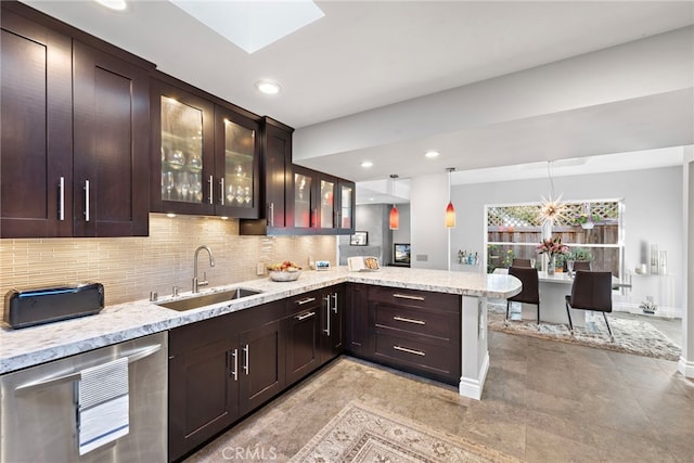 kitchen with light stone countertops, hanging light fixtures, sink, kitchen peninsula, and backsplash