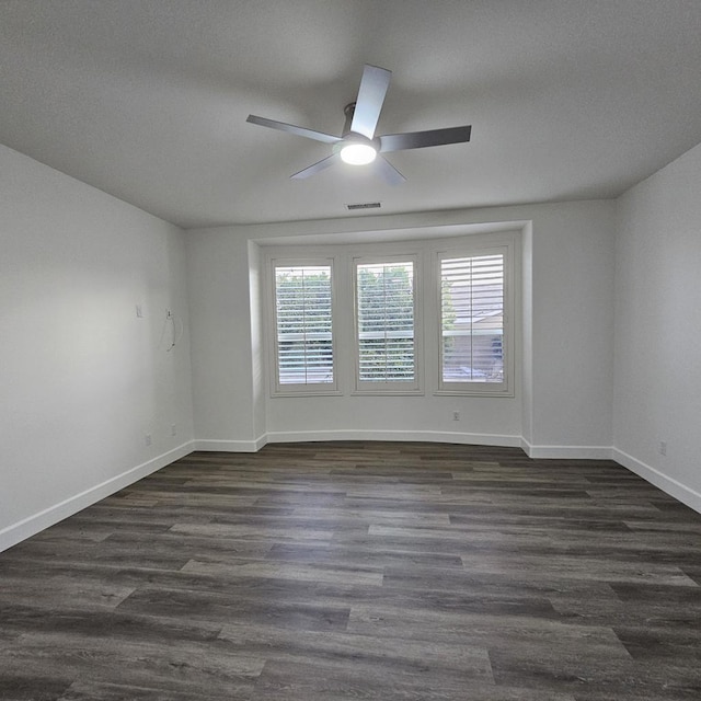 spare room featuring dark wood-type flooring, plenty of natural light, and ceiling fan