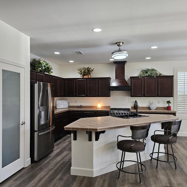 kitchen featuring stainless steel refrigerator with ice dispenser, sink, a center island with sink, and custom range hood