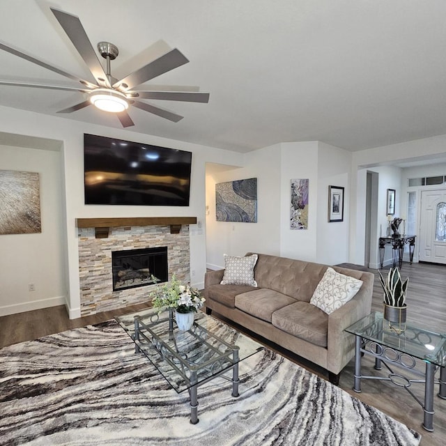 living room featuring ceiling fan, a stone fireplace, and hardwood / wood-style flooring