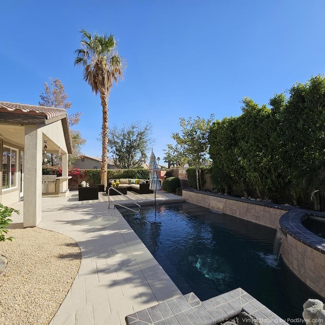 view of swimming pool with outdoor lounge area, an outdoor kitchen, pool water feature, and a patio