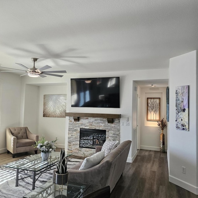 living room featuring ceiling fan, dark hardwood / wood-style floors, and a stone fireplace