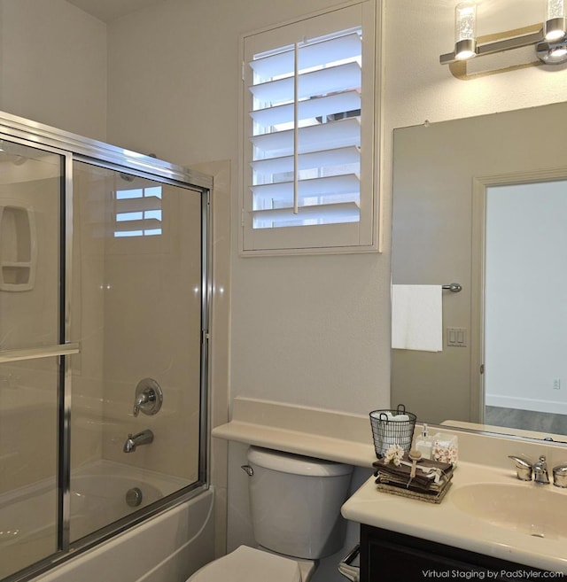 full bathroom with enclosed tub / shower combo, vanity, and toilet