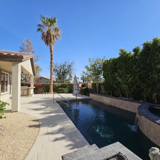 view of swimming pool featuring pool water feature, exterior kitchen, and a patio area