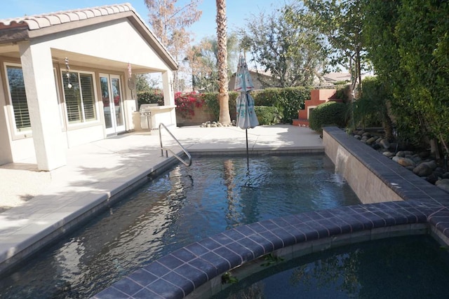 view of pool with area for grilling, french doors, and a patio