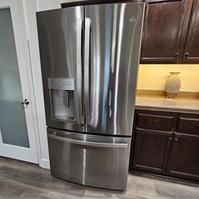 kitchen featuring stainless steel refrigerator with ice dispenser, tile countertops, light hardwood / wood-style floors, and dark brown cabinets