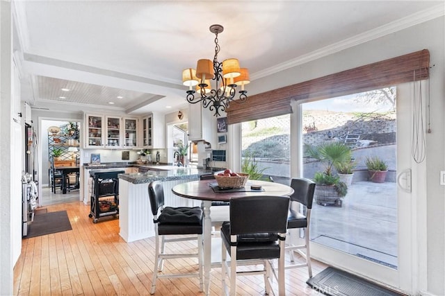 dining area with light hardwood / wood-style floors, sink, crown molding, and a notable chandelier