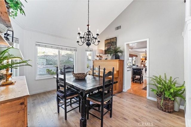 dining space with high vaulted ceiling, a chandelier, and light wood-type flooring