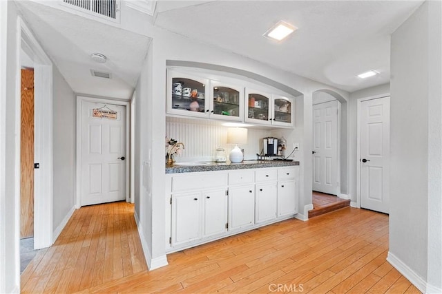 bar with sink, white cabinetry, and light hardwood / wood-style flooring