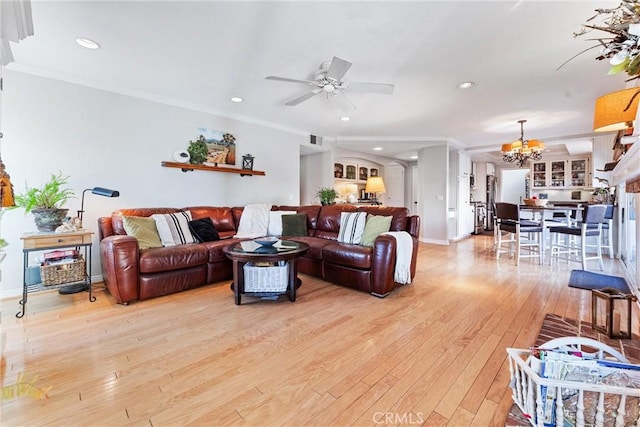 living room featuring ceiling fan with notable chandelier, ornamental molding, and light hardwood / wood-style floors