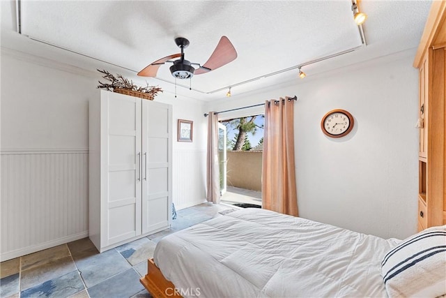 bedroom featuring ceiling fan, track lighting, and a textured ceiling