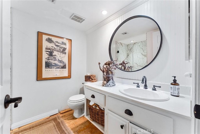 bathroom featuring toilet, vanity, ornamental molding, and hardwood / wood-style floors