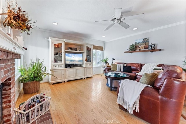 living room with ceiling fan, light hardwood / wood-style flooring, crown molding, and a fireplace