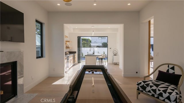 game room with a fireplace, light hardwood / wood-style floors, and sink