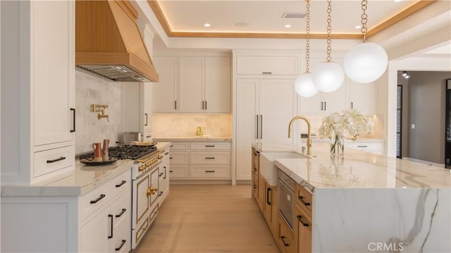 kitchen with a spacious island, decorative light fixtures, white cabinets, custom range hood, and light stone counters