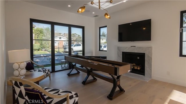 playroom with a high end fireplace and light hardwood / wood-style flooring