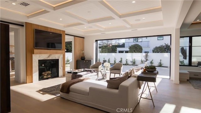 living room with beam ceiling, a premium fireplace, and coffered ceiling