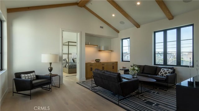 living room with a wealth of natural light, light hardwood / wood-style flooring, and beamed ceiling