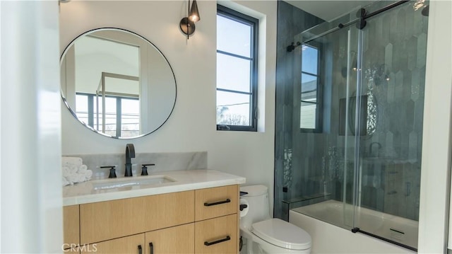 full bathroom featuring toilet, vanity, plenty of natural light, and shower / bath combination with glass door