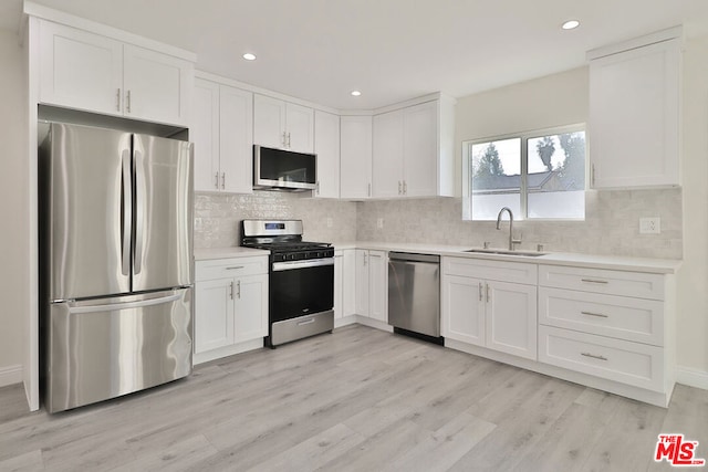 kitchen with sink, white cabinetry, stainless steel appliances, and light wood-type flooring