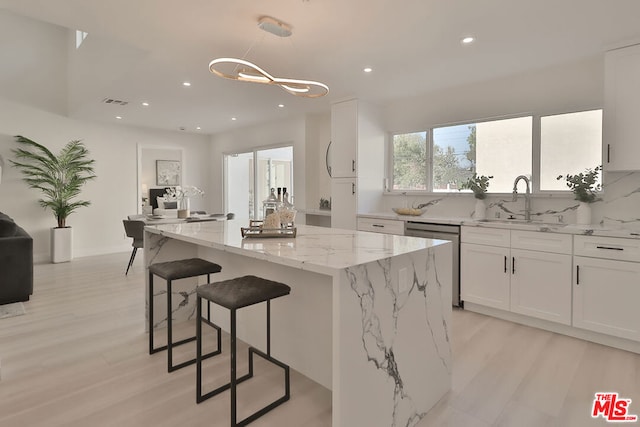 kitchen with white cabinetry, dishwasher, and a kitchen island