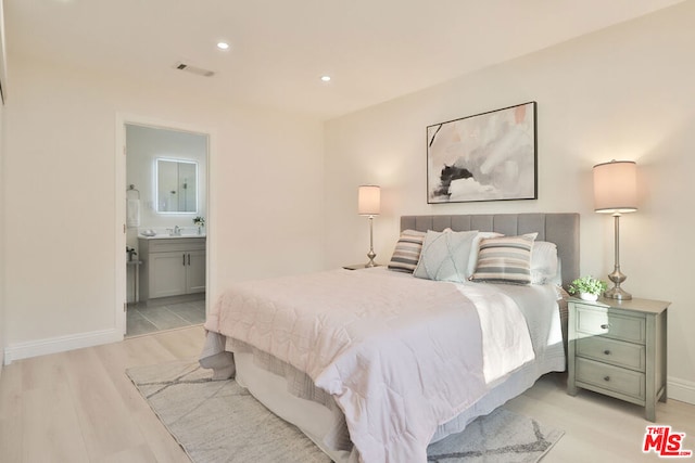 bedroom featuring ensuite bathroom and light hardwood / wood-style flooring