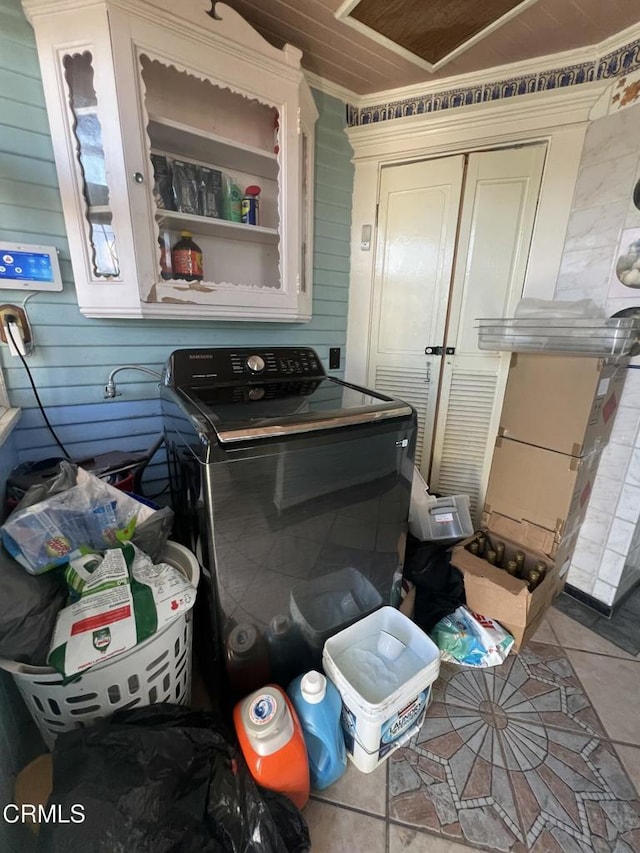 washroom with tile patterned flooring, wood walls, and washer / dryer