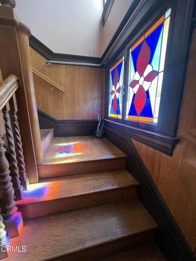 staircase featuring wooden walls