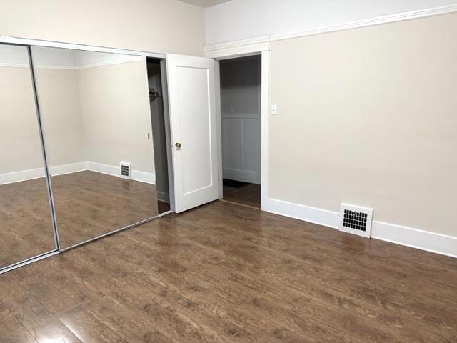 unfurnished bedroom with dark wood-type flooring and a closet