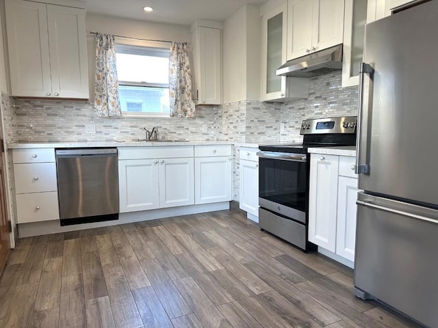 kitchen with sink, white cabinetry, tasteful backsplash, hardwood / wood-style flooring, and stainless steel appliances