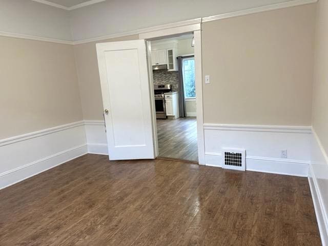 spare room with ornamental molding and dark hardwood / wood-style floors