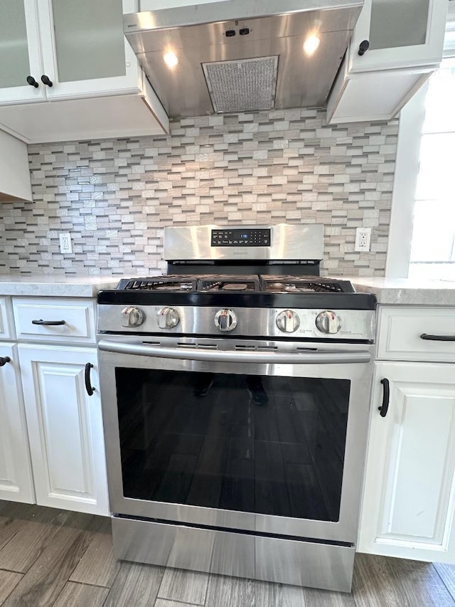 kitchen featuring tasteful backsplash, double oven range, exhaust hood, and white cabinets