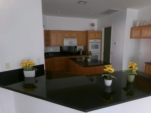 kitchen featuring sink, kitchen peninsula, and white appliances