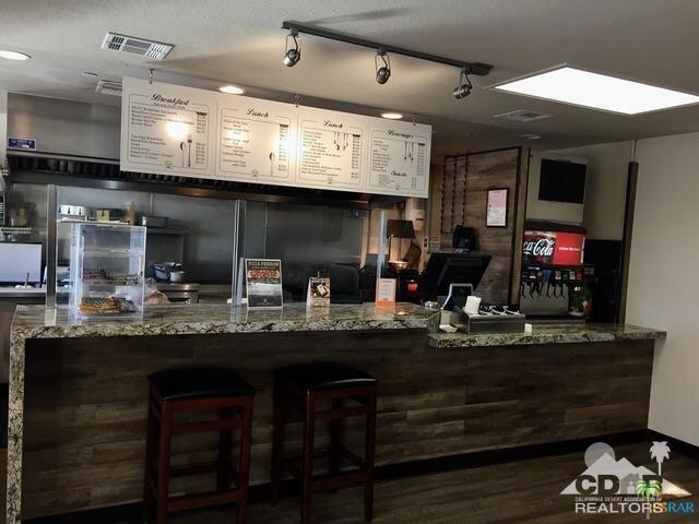 bar featuring dark hardwood / wood-style flooring, stone countertops, and a textured ceiling