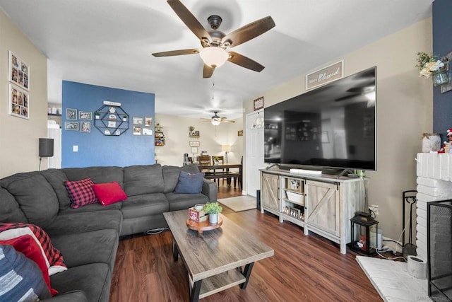 living room featuring dark wood-type flooring, a fireplace, and ceiling fan