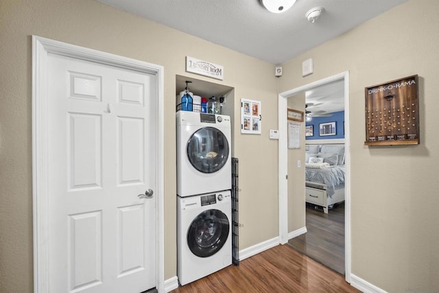 clothes washing area featuring ceiling fan, wood-type flooring, and stacked washer and dryer