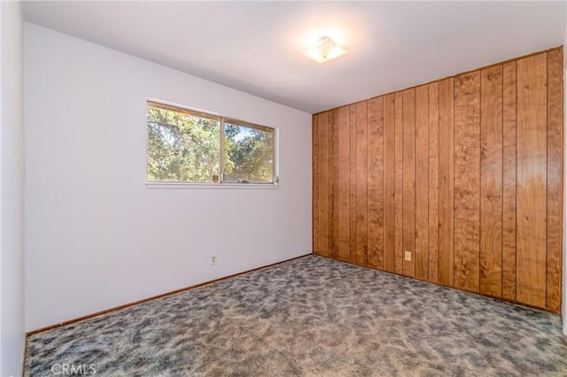 carpeted spare room with wooden walls