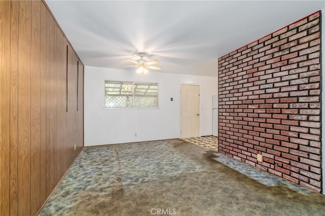 interior space with carpet floors, brick wall, ceiling fan, and wooden walls