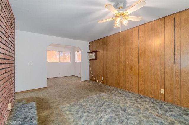 spare room with ceiling fan, a wall mounted AC, light colored carpet, and wooden walls