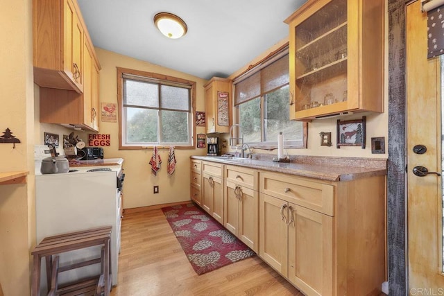 kitchen featuring sink, lofted ceiling, light wood-type flooring, stove, and light brown cabinets