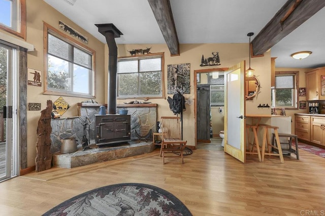 sitting room featuring light hardwood / wood-style flooring, lofted ceiling with beams, a wood stove, and radiator