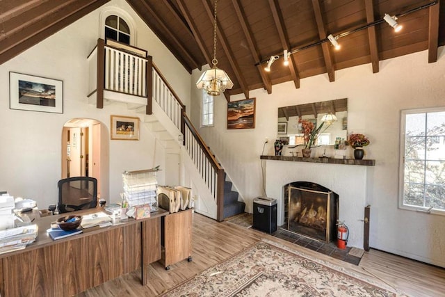 living room with wood ceiling, an inviting chandelier, lofted ceiling with beams, a tile fireplace, and light hardwood / wood-style floors