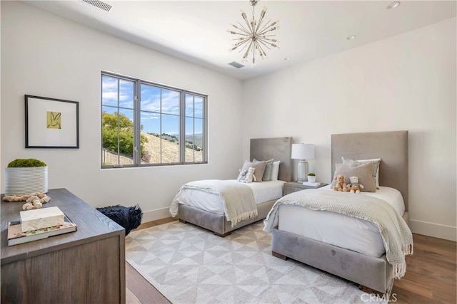 bedroom with light hardwood / wood-style flooring and an inviting chandelier