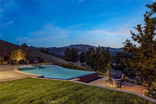 view of swimming pool featuring a mountain view, a patio area, and a lawn