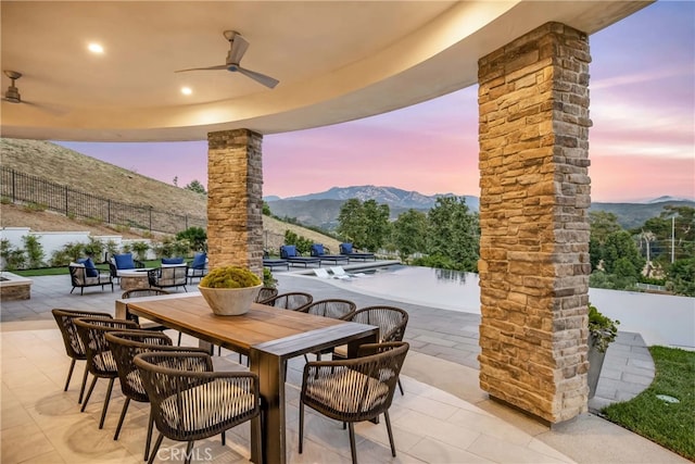 patio terrace at dusk with a mountain view and ceiling fan