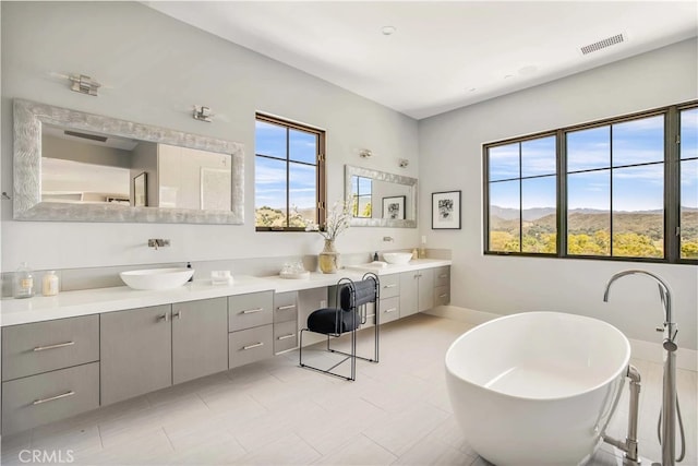 bathroom with a bathing tub, a healthy amount of sunlight, a mountain view, and vanity