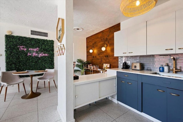 kitchen featuring white cabinetry, backsplash, blue cabinets, a textured ceiling, and sink